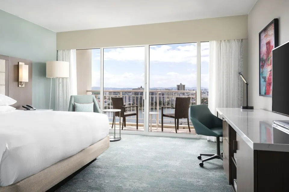 King guest room with balcony seating and city view at Caribe Hilton.