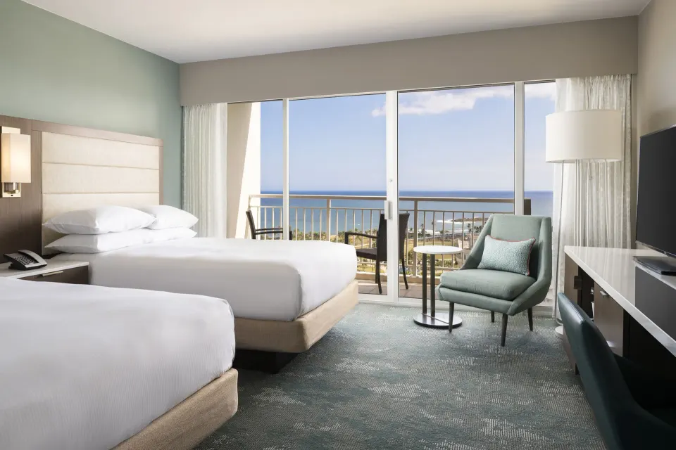 Two double beds and balcony ocean view in a guest room at Caribe Hilton.