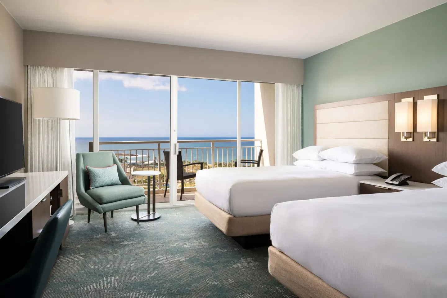 Guest room with two double beds, balcony, and ocean view at Caribe Hilton.
