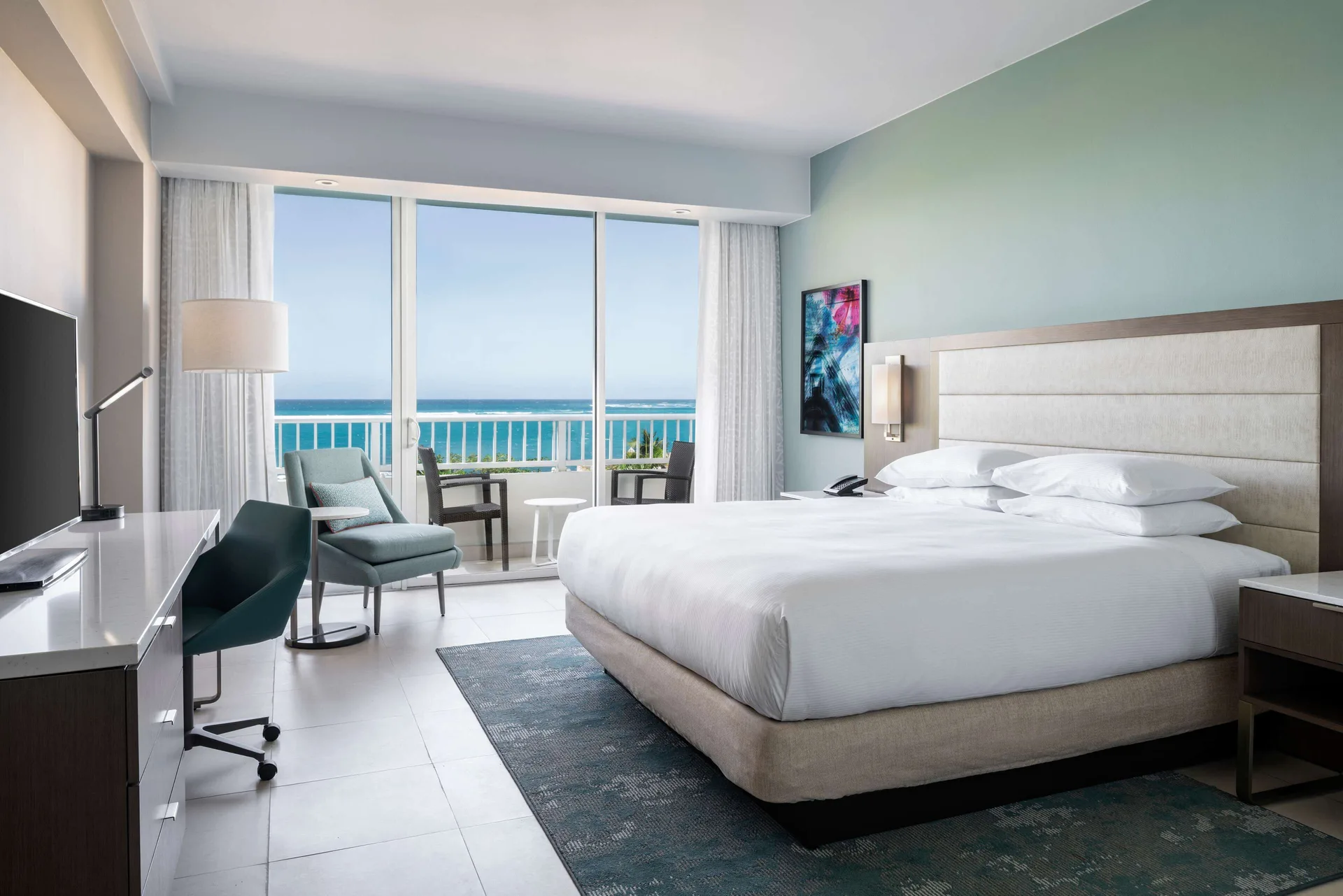 Premium garden view king guest room with balcony seating at Caribe Hilton.