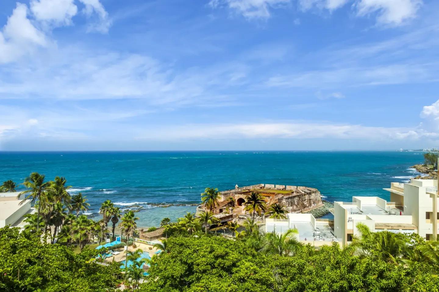 Ocean, palms, and historic fort view from a Premium Garden View room at Caribe Hilton.