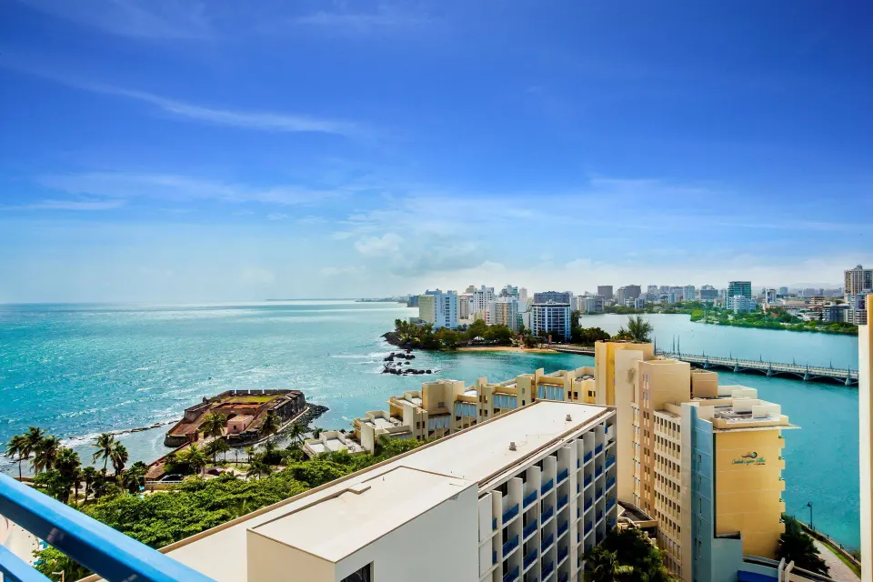 Balcony view of the coastline, lagoon, and city skyline from a guest room at Caribe Hilton.