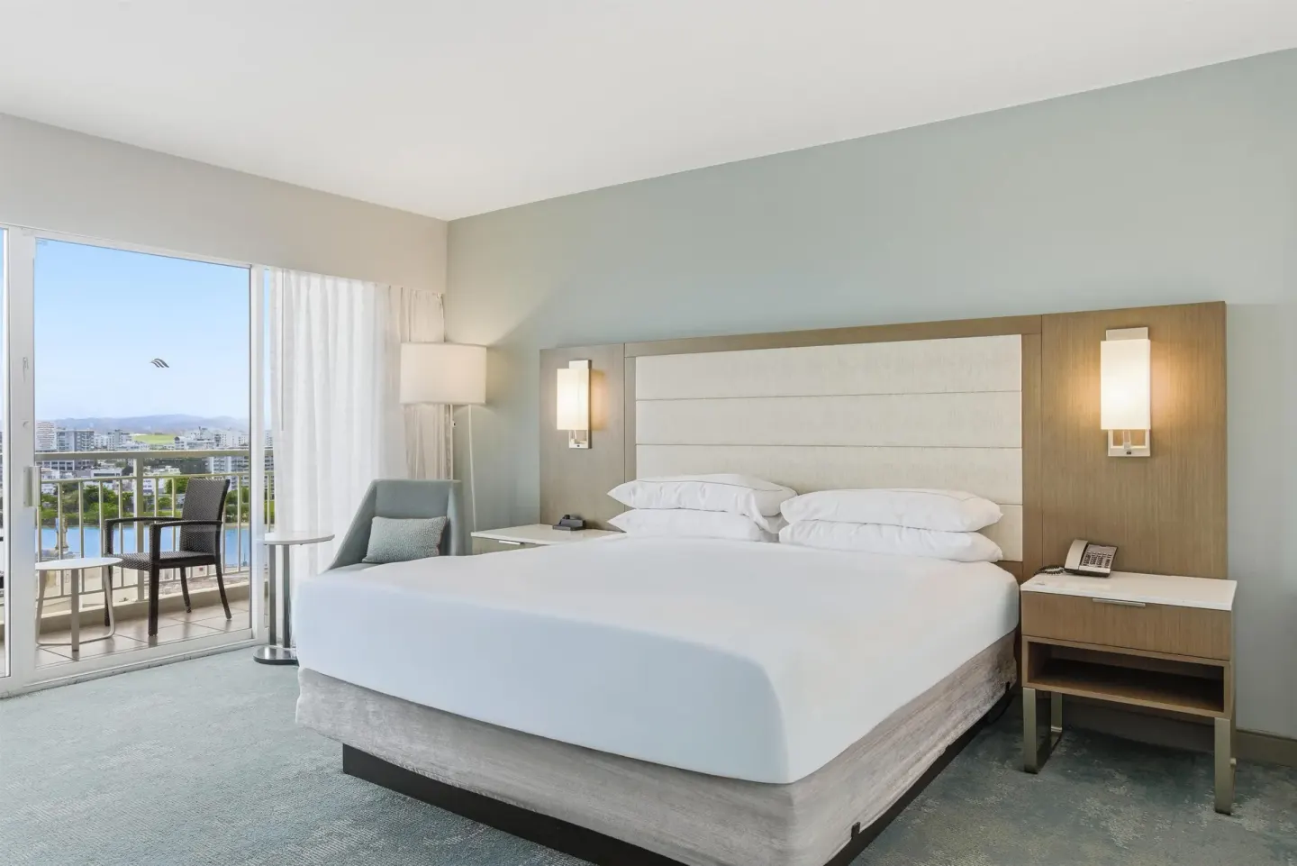 King bed in a high-floor ocean view guest room with balcony at Caribe Hilton.