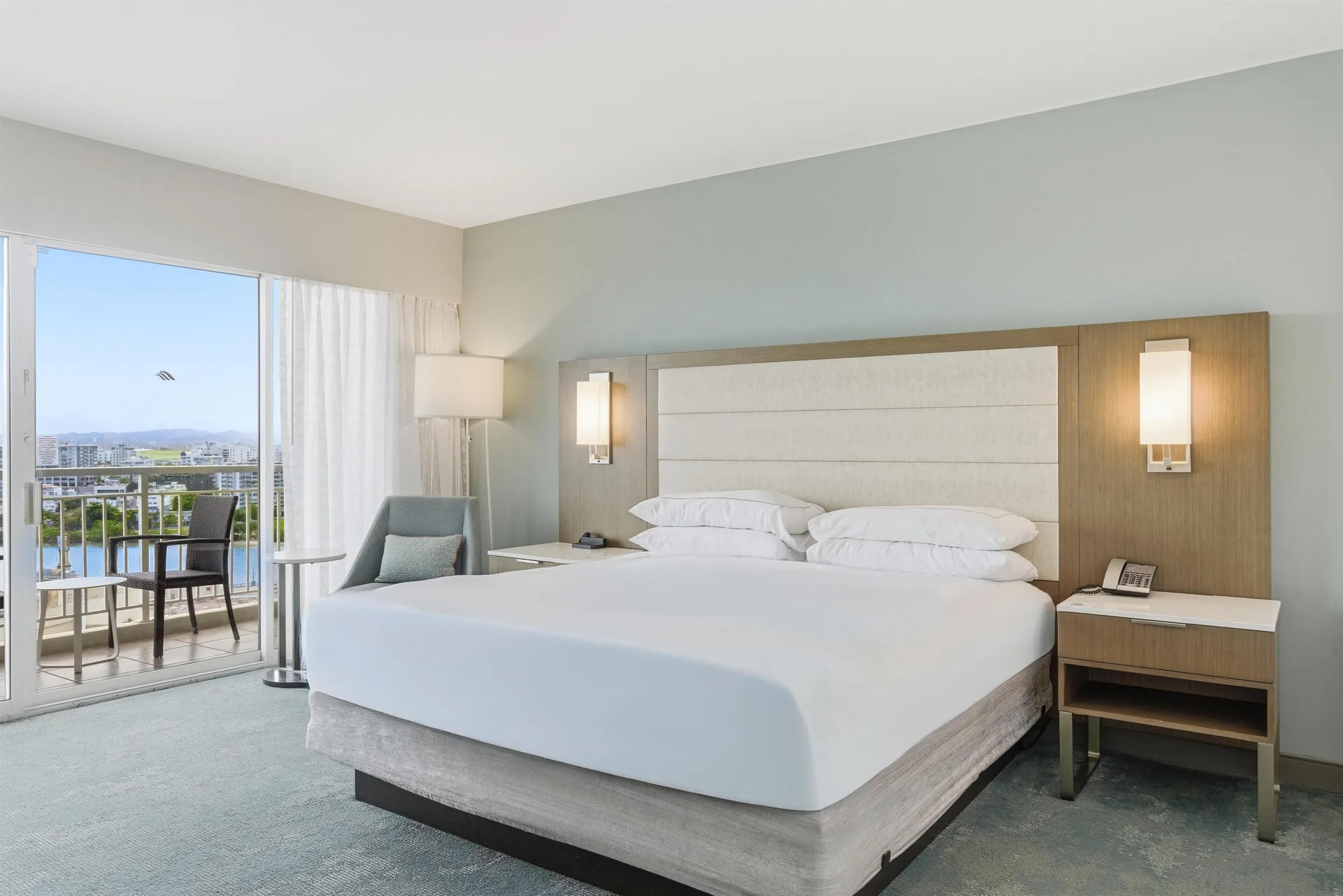 King bed in a high-floor ocean view guest room with balcony at Caribe Hilton.
