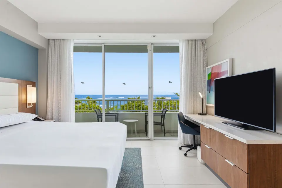 Family Room Garden View with a bed, TV console, desk, and balcony at Caribe Hilton.