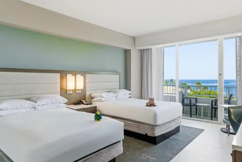 Family Room Garden View with two beds and a balcony facing palms and ocean at Caribe Hilton.