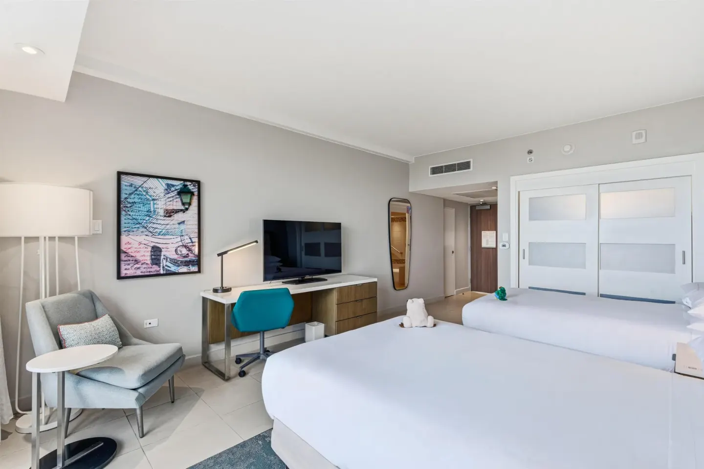 Family Room Garden View with two beds, desk, TV, and lounge chair at Caribe Hilton.