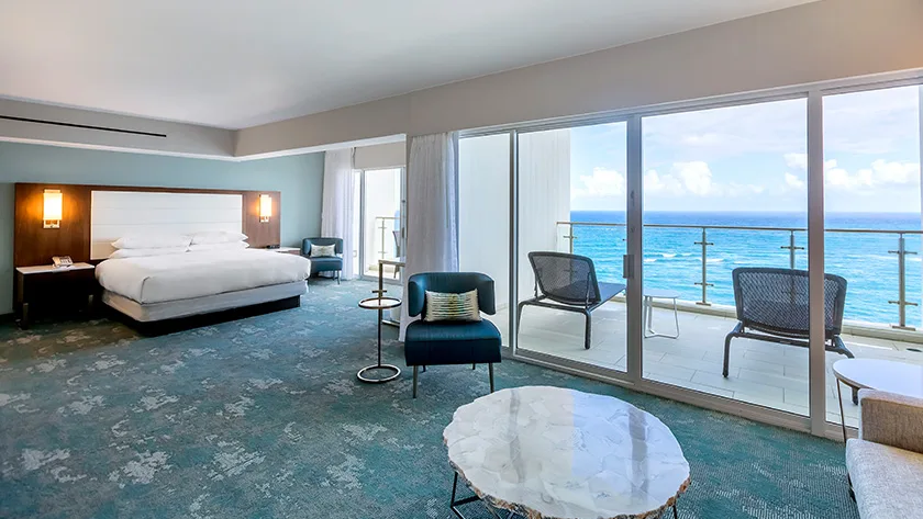 Family Room with king bed, seating area, balcony, and ocean view at Caribe Hilton.