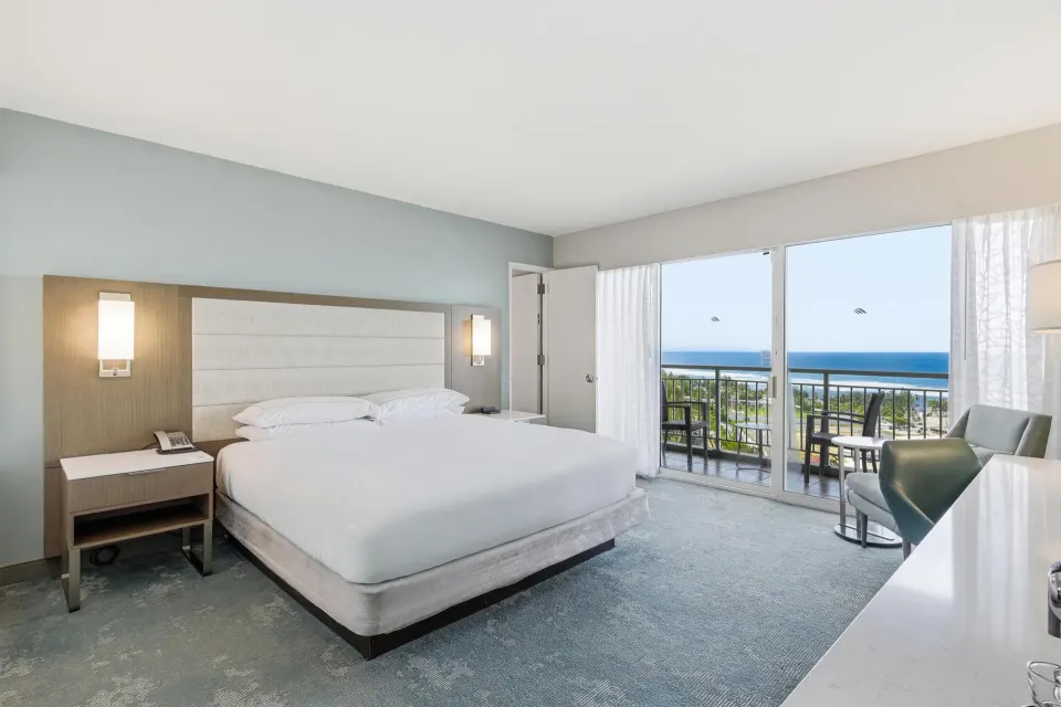 Family Room Ocean View king bed with balcony and ocean beyond at Caribe Hilton.
