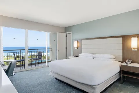 Family Room Ocean View king bed beside sliding balcony doors at Caribe Hilton.