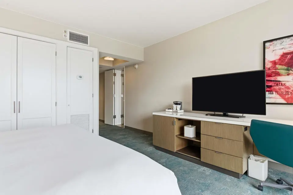 Family Room Ocean View king bed with TV console and desk chair at Caribe Hilton.