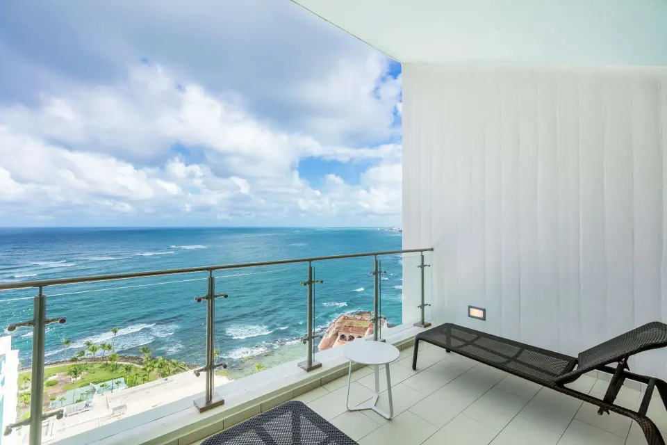Honeymoon suite balcony with lounge chairs and ocean view at Caribe Hilton.
