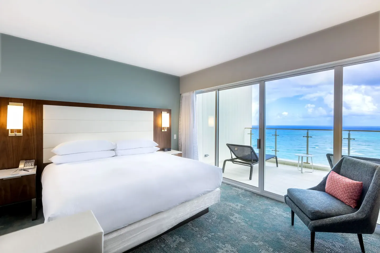 King bed and oceanfront balcony in a Honeymoon Suite at Caribe Hilton.