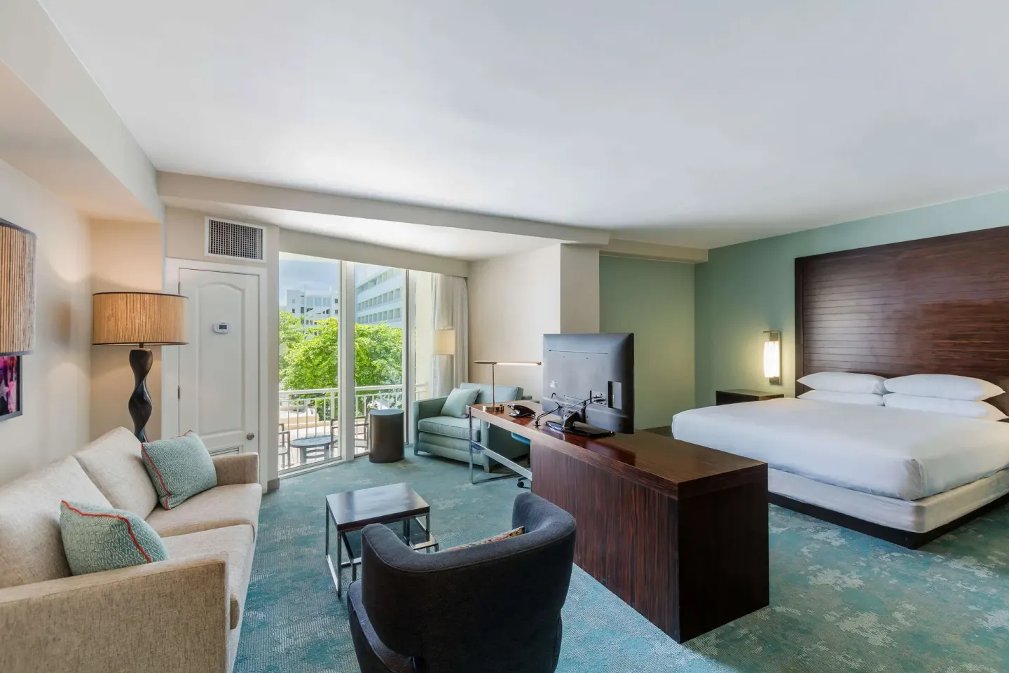 Junior Suite king bed and sofabed living area with balcony doors at Caribe Hilton.