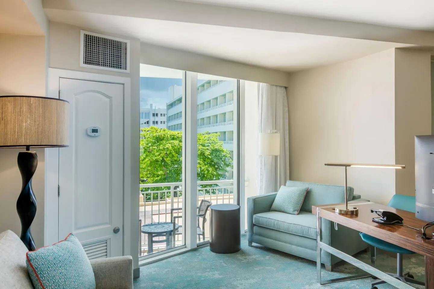 Junior suite living area with balcony seating and desk at Caribe Hilton.