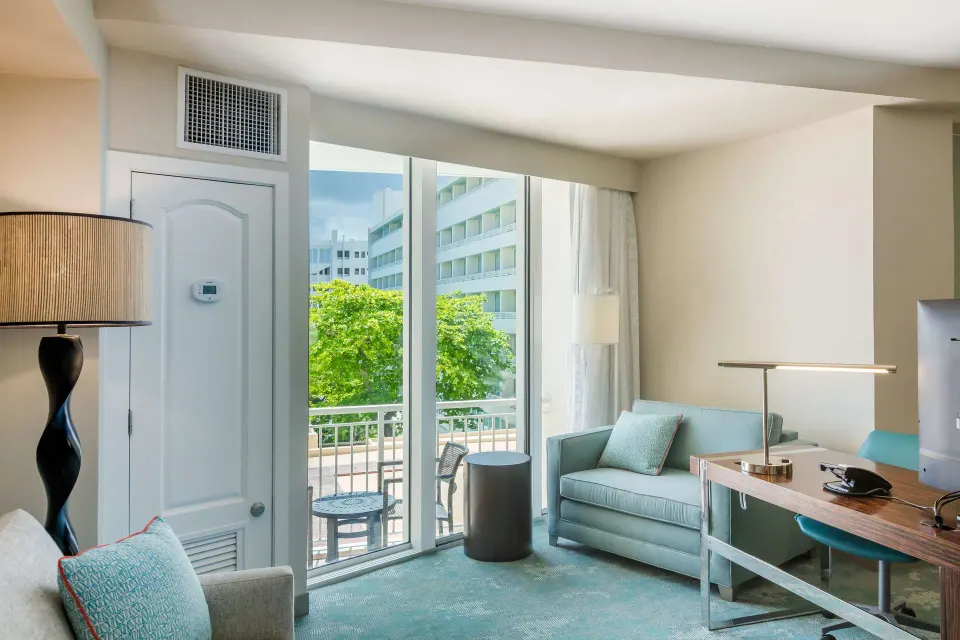 Junior suite living area with balcony seating and desk at Caribe Hilton.