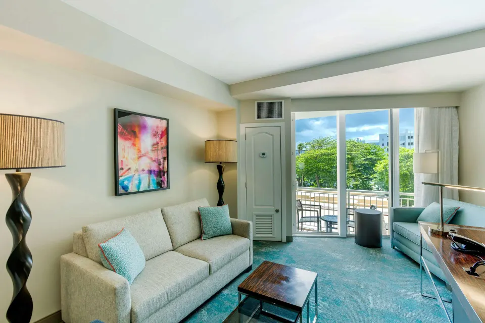 Junior Suite sofabed seating area with balcony doors at Caribe Hilton.