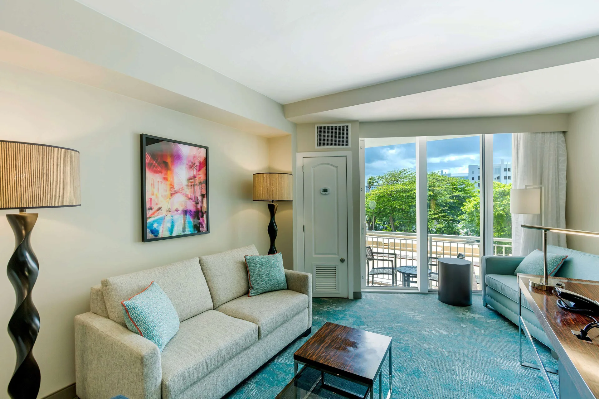 Junior Suite sofabed seating area with balcony doors at Caribe Hilton.