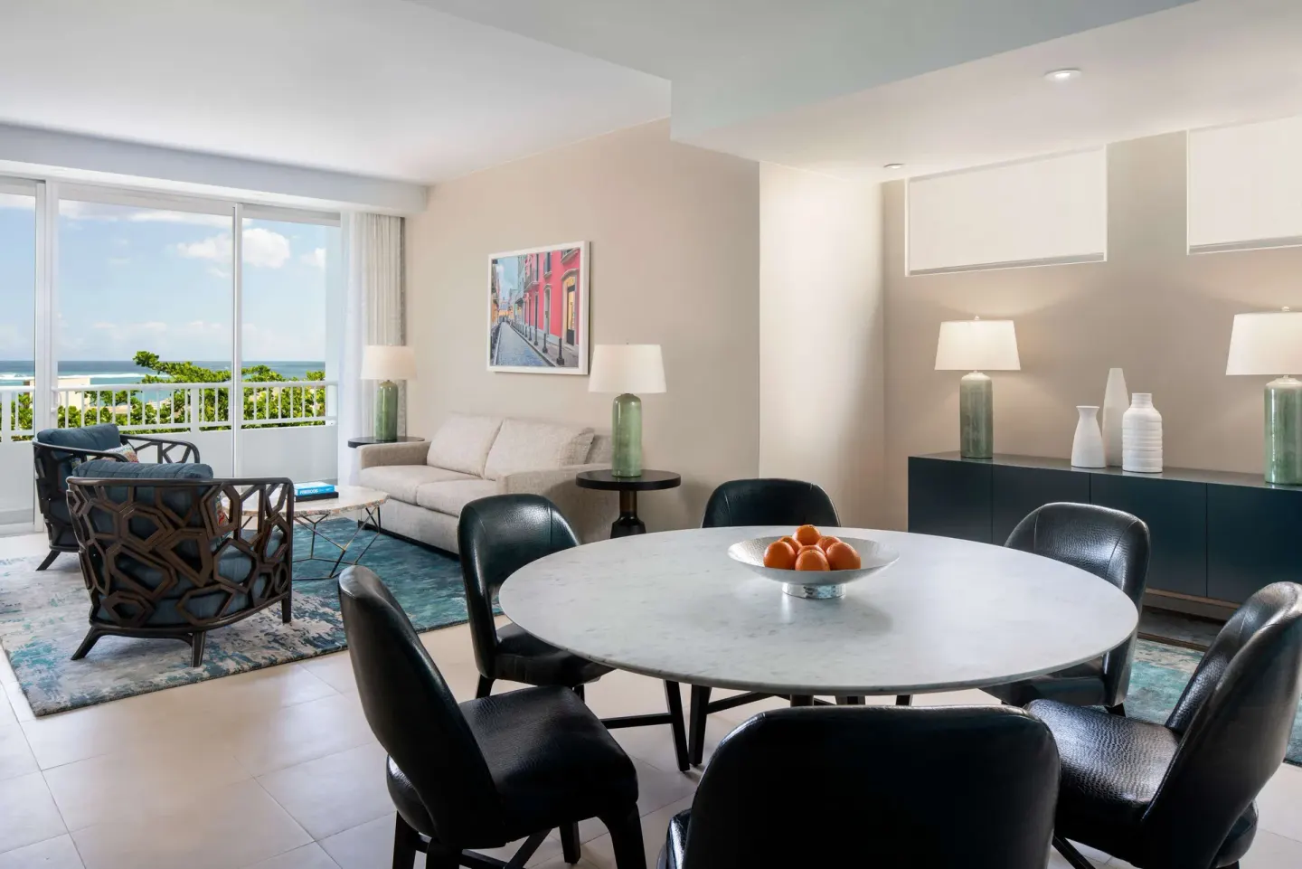 Premium suite dining and living area at Caribe Hilton with round table, sofa and balcony doors.