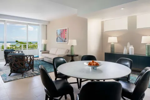 Premium suite dining and living area at Caribe Hilton with round table, sofa and balcony doors.