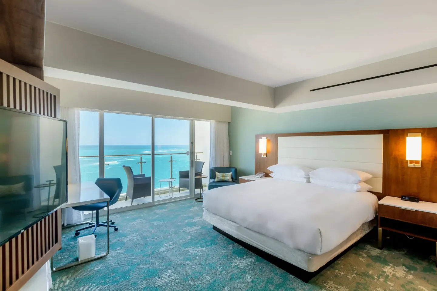 Ocean-view king bedroom with balcony doors and desk in the Presidential suite at Caribe Hilton.