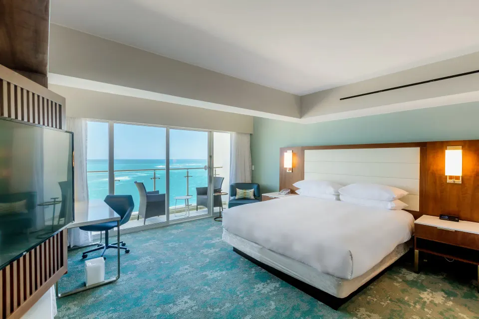 Ocean-view king bedroom with balcony doors and desk in the Presidential suite at Caribe Hilton.