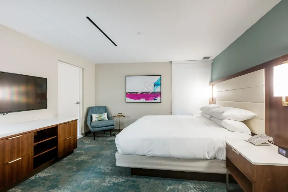 Presidential two-bedroom suite king bedroom with TV and lounge chair at Caribe Hilton.