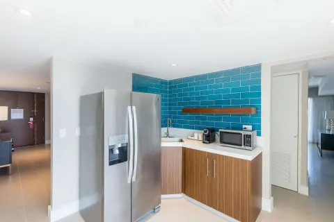 Presidential suite kitchenette with refrigerator, sink, microwave, and blue tile at Caribe Hilton.