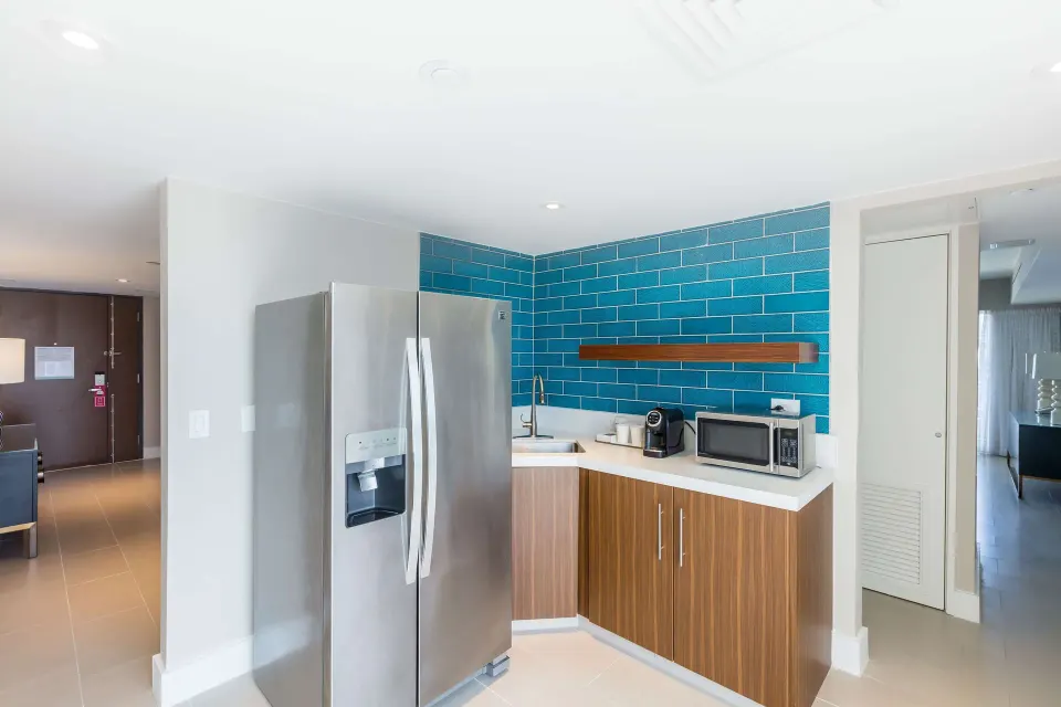Presidential suite kitchenette with refrigerator, sink, microwave, and blue tile at Caribe Hilton.