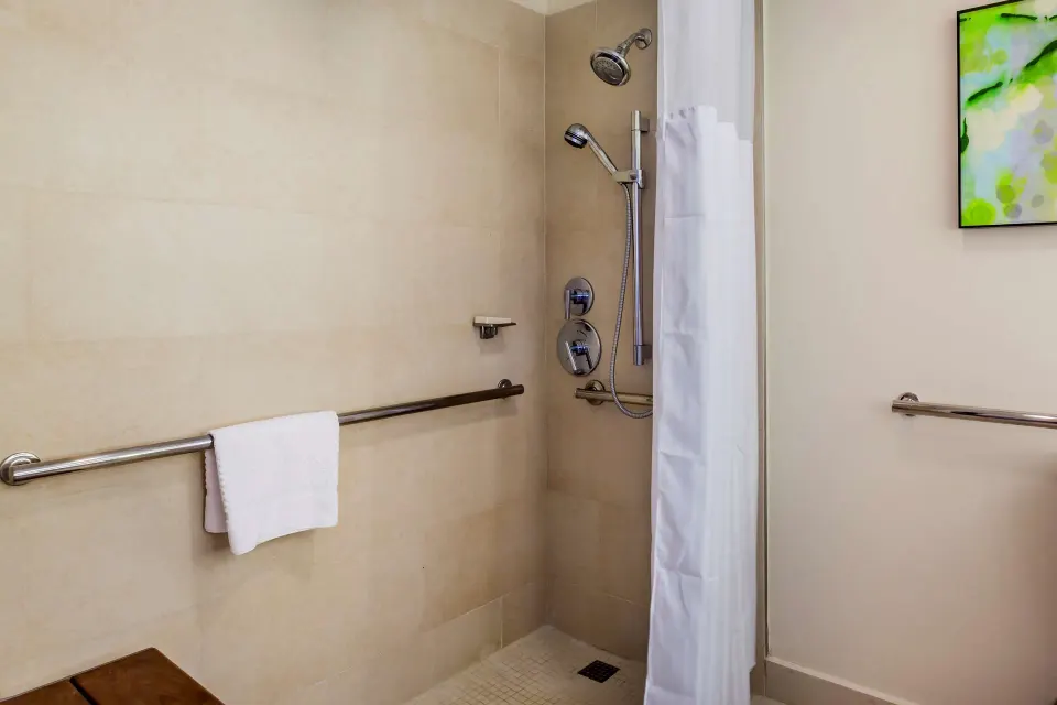 Accessible roll-in shower with grab bars in a guest room bathroom at Caribe Hilton.