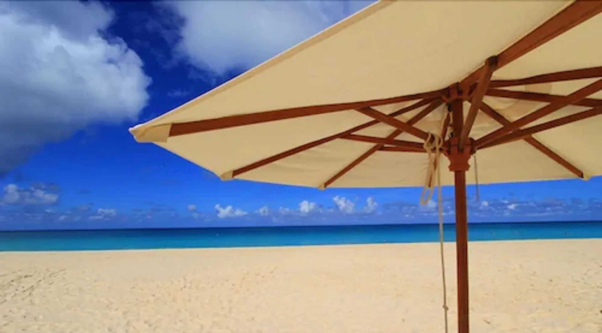 Close-up of a beach umbrella over sand and turquoise sea at Carimar Beach Club.