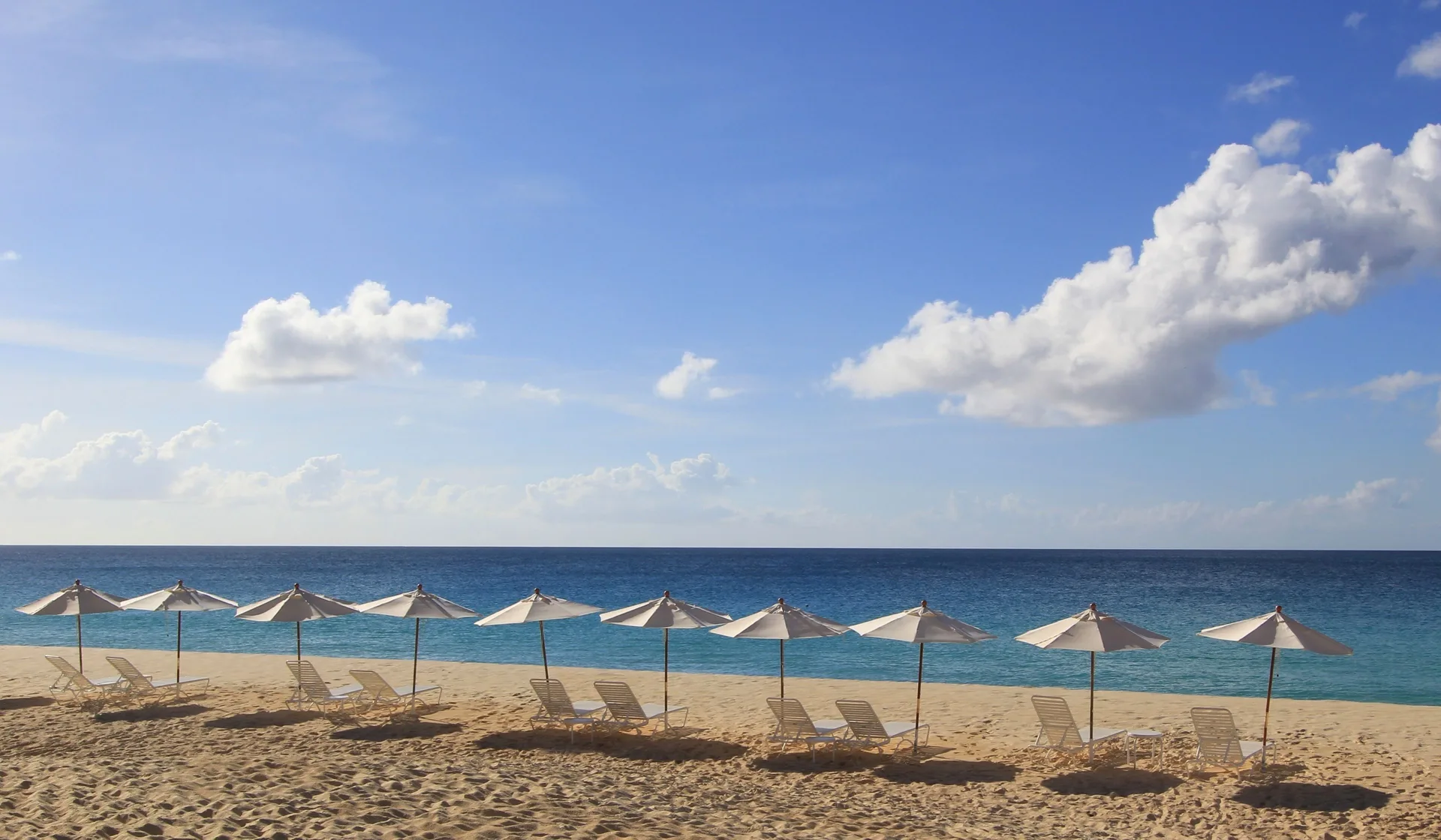 Rows of beach umbrellas and lounge chairs facing the ocean at Carimar Beach Club.