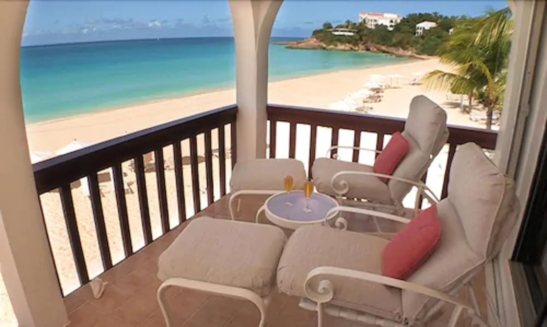 Cushioned balcony chairs overlook the beach and turquoise sea at Carimar Beach Club.