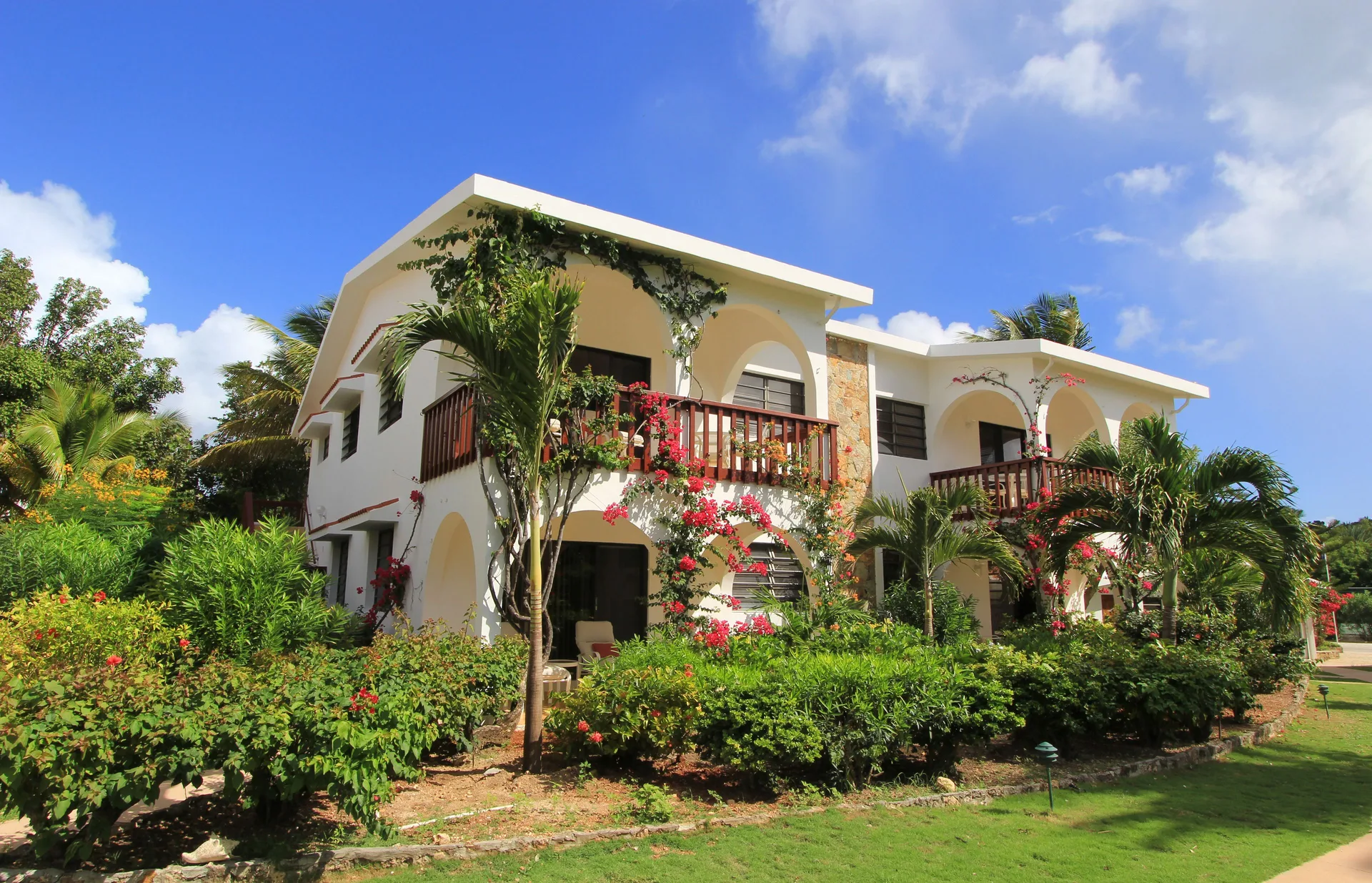 White resort building with balconies and tropical gardens at Carimar Beach Club.