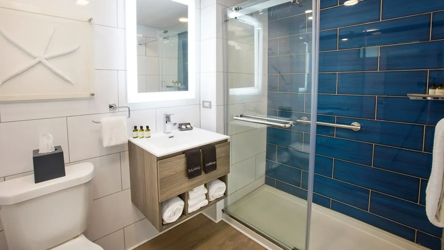 Bathroom vanity and blue-tile glass shower at Carina Bay Boutique Resort & Casino.