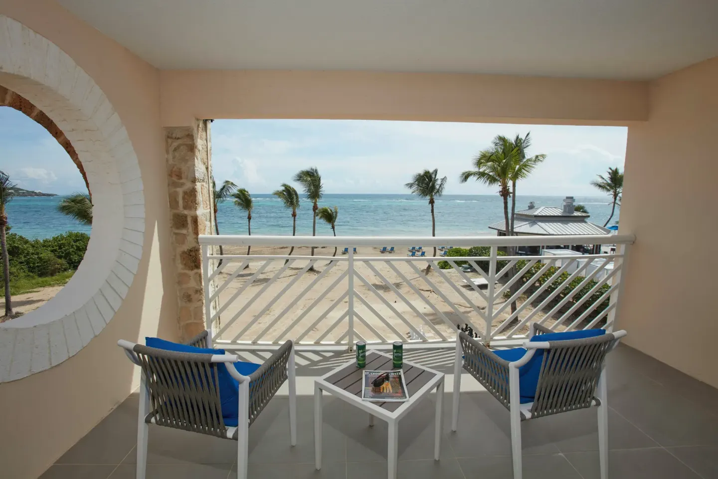 Covered balcony at Carina Bay Boutique Resort & Casino overlooking palms, beach, and the ocean.
