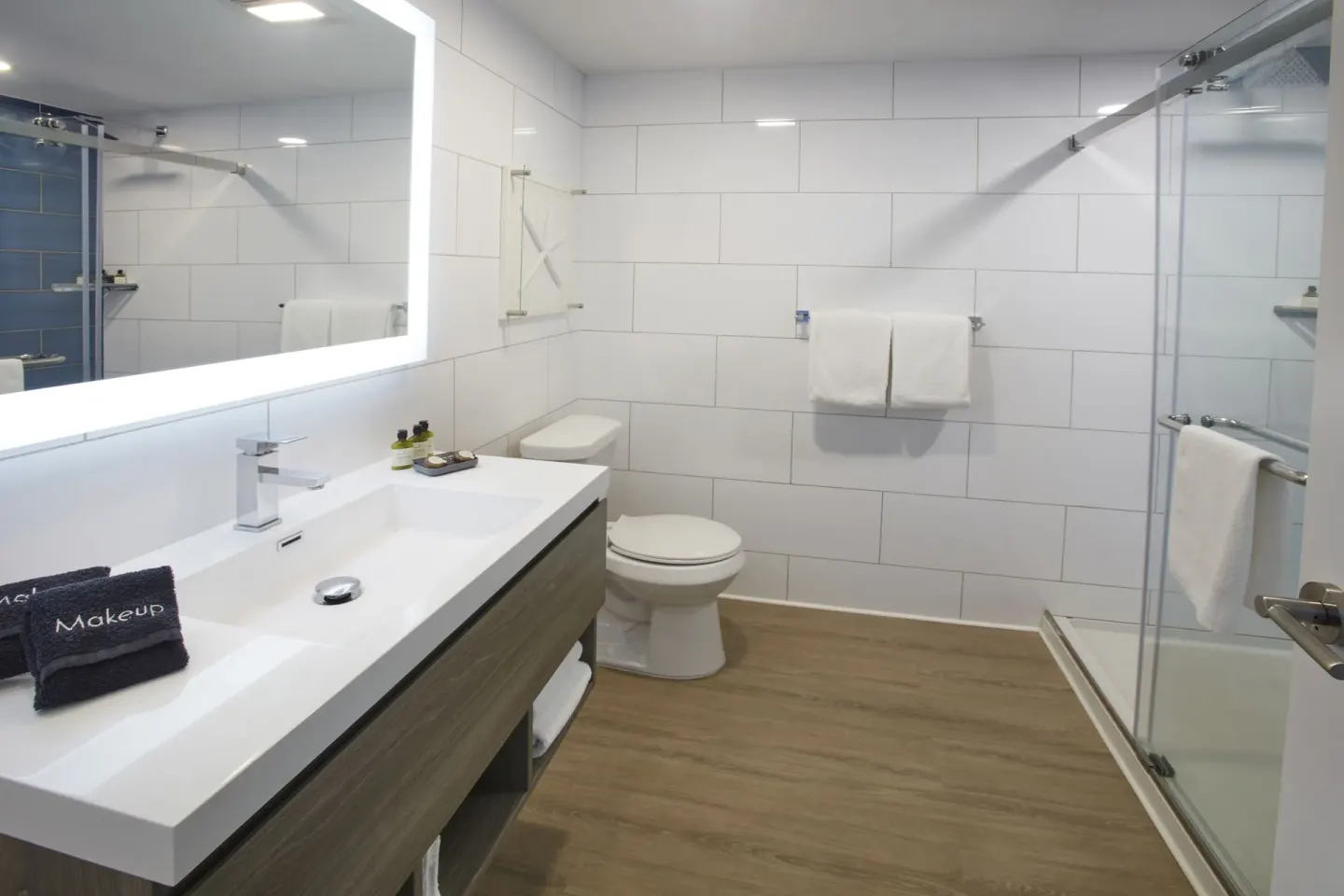 Guest bathroom at Carina Bay Boutique Resort & Casino with long vanity, toilet, and glass shower.