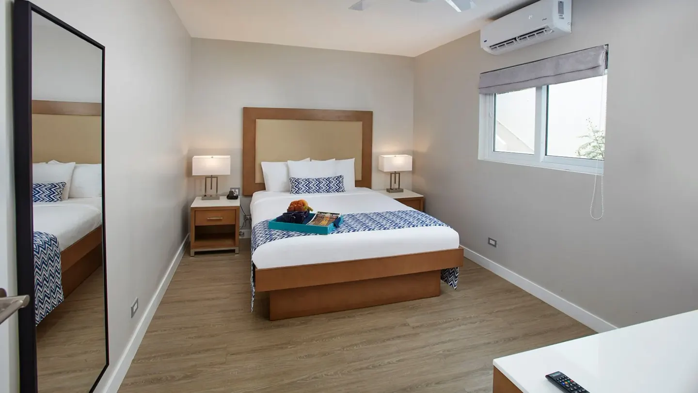 King-bed guest room with window and bedside lamps at Carina Bay Boutique Resort & Casino.