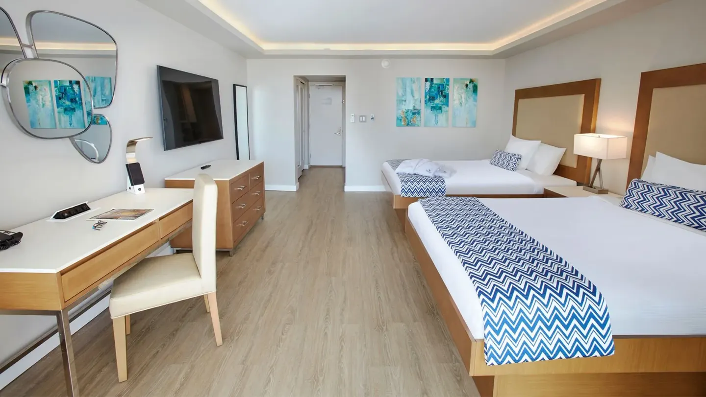 Double-bed guest room with desk and dresser at Carina Bay Boutique Resort & Casino.