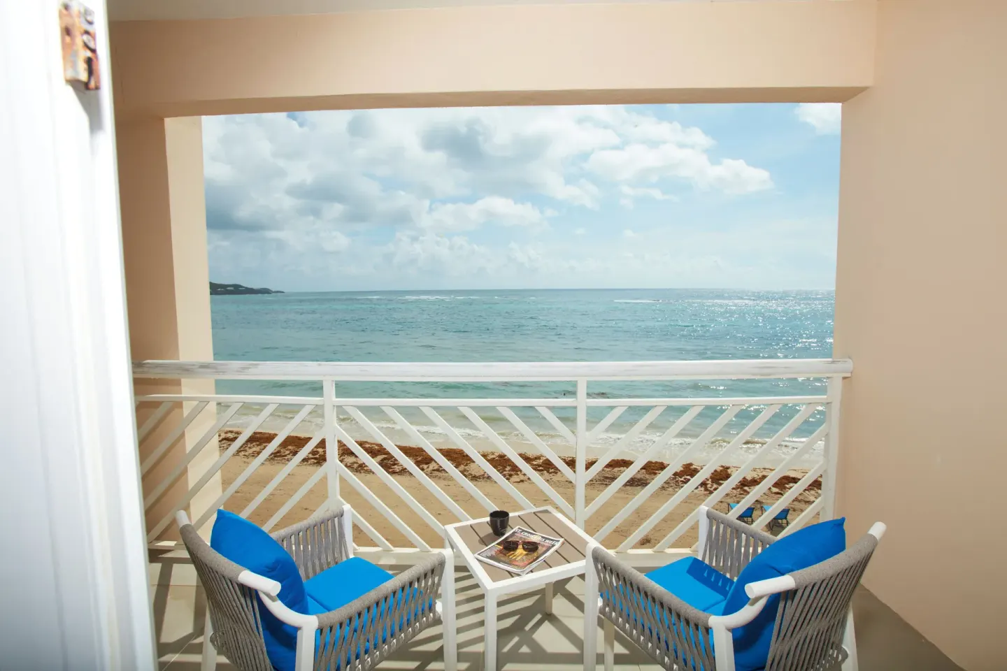 Oceanfront balcony seating at Carina Bay Boutique Resort & Casino with blue chairs and a small table.