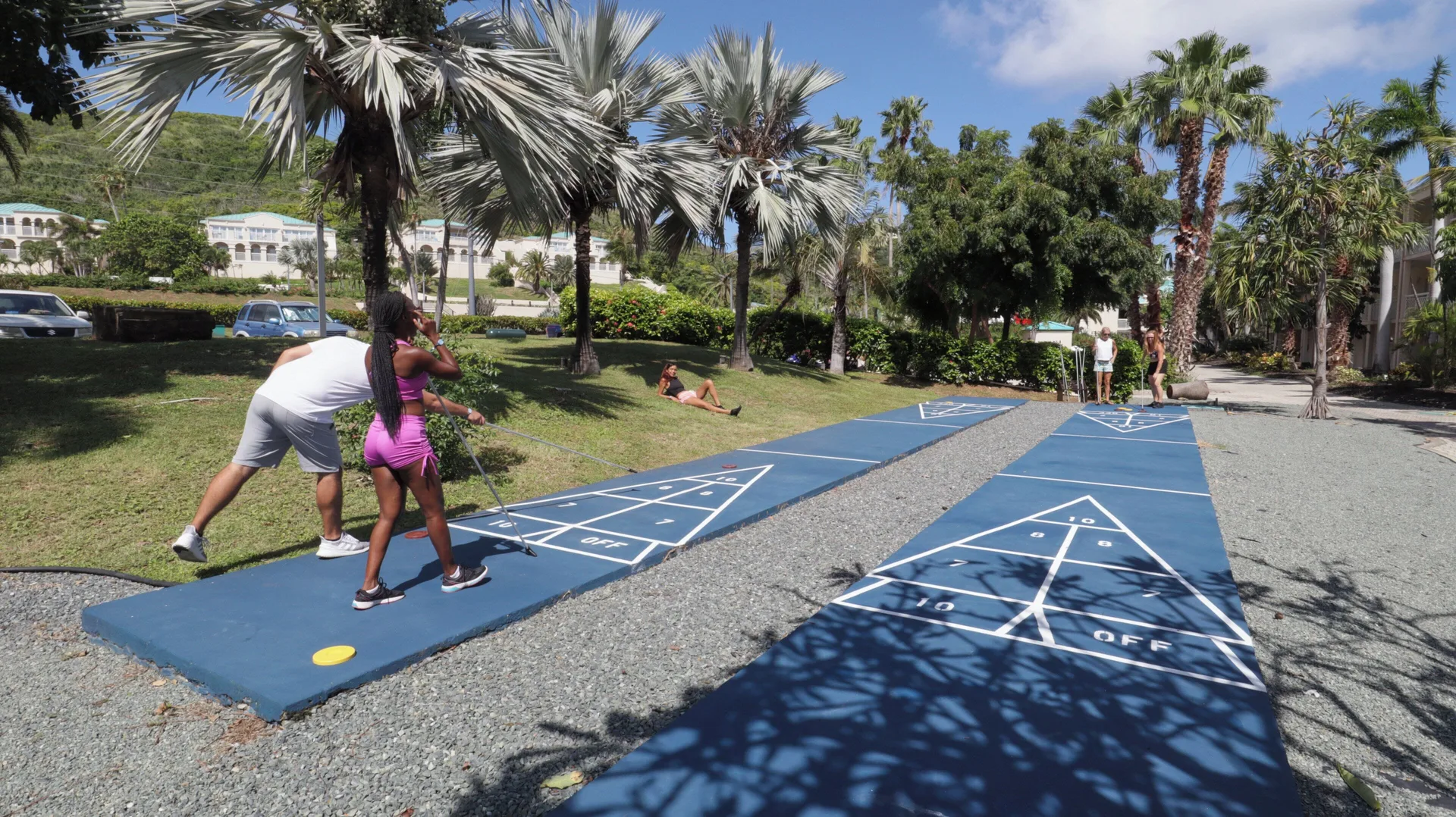 Guests play shuffleboard on landscaped grounds at Carina Bay Boutique Resort & Casino.
