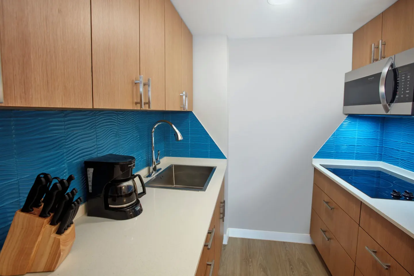 Galley kitchen with sink and cooktop at Carina Bay Boutique Resort & Casino.