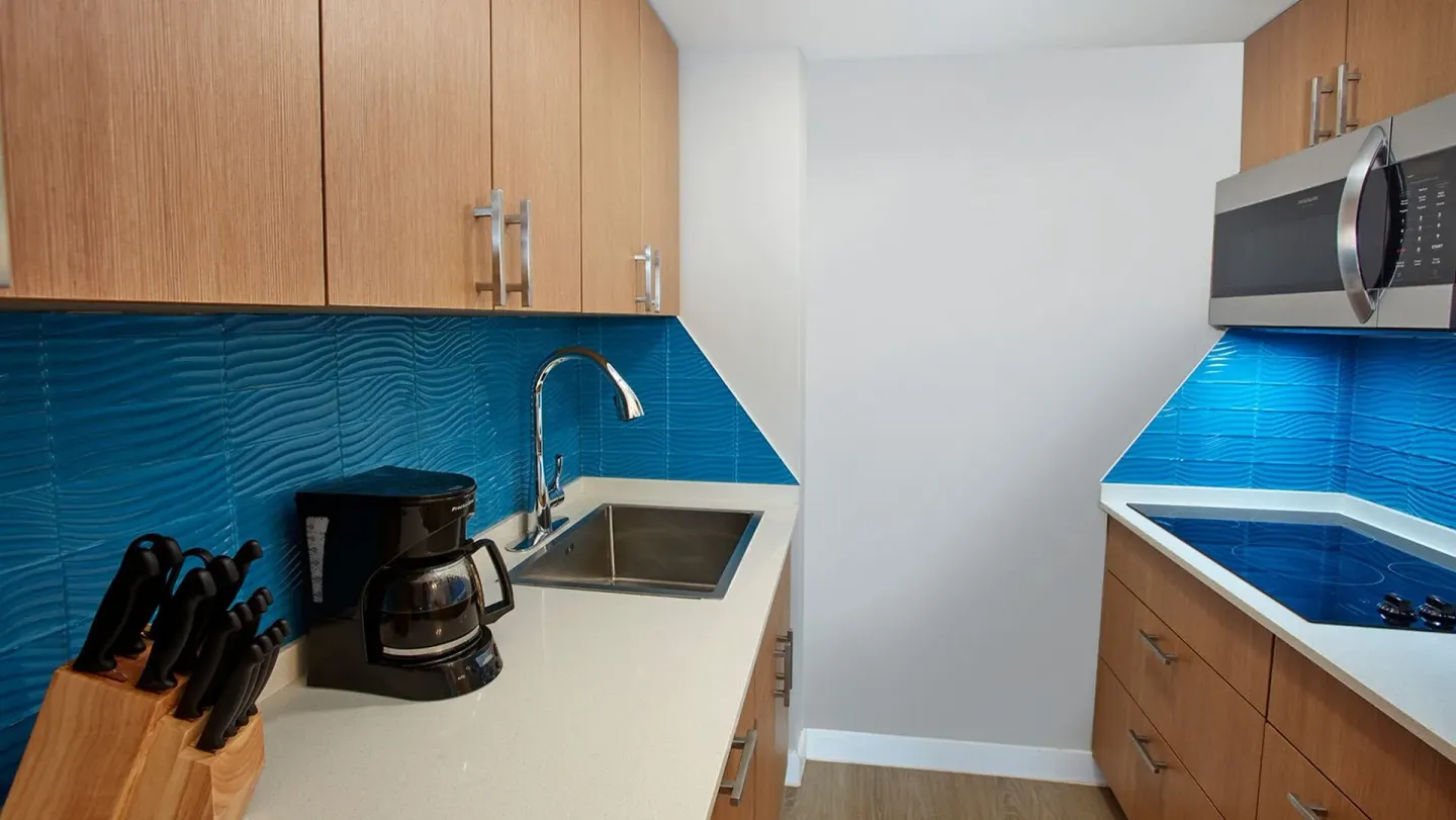 Compact kitchen with blue tile backsplash at Carina Bay Boutique Resort & Casino.