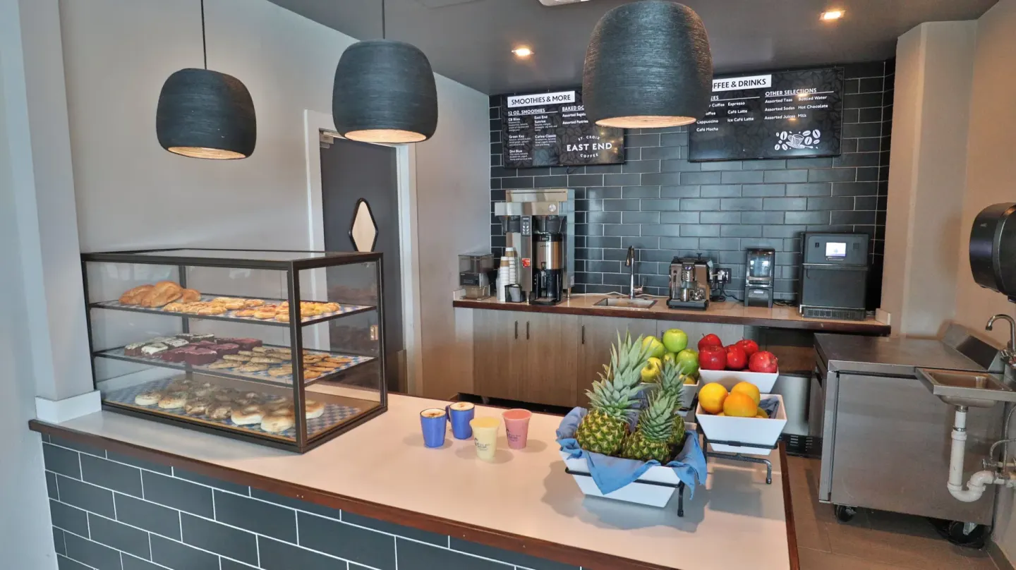 East End Coffee counter at Carina Bay Boutique Resort & Casino with pastries, fruit, and drink menus.