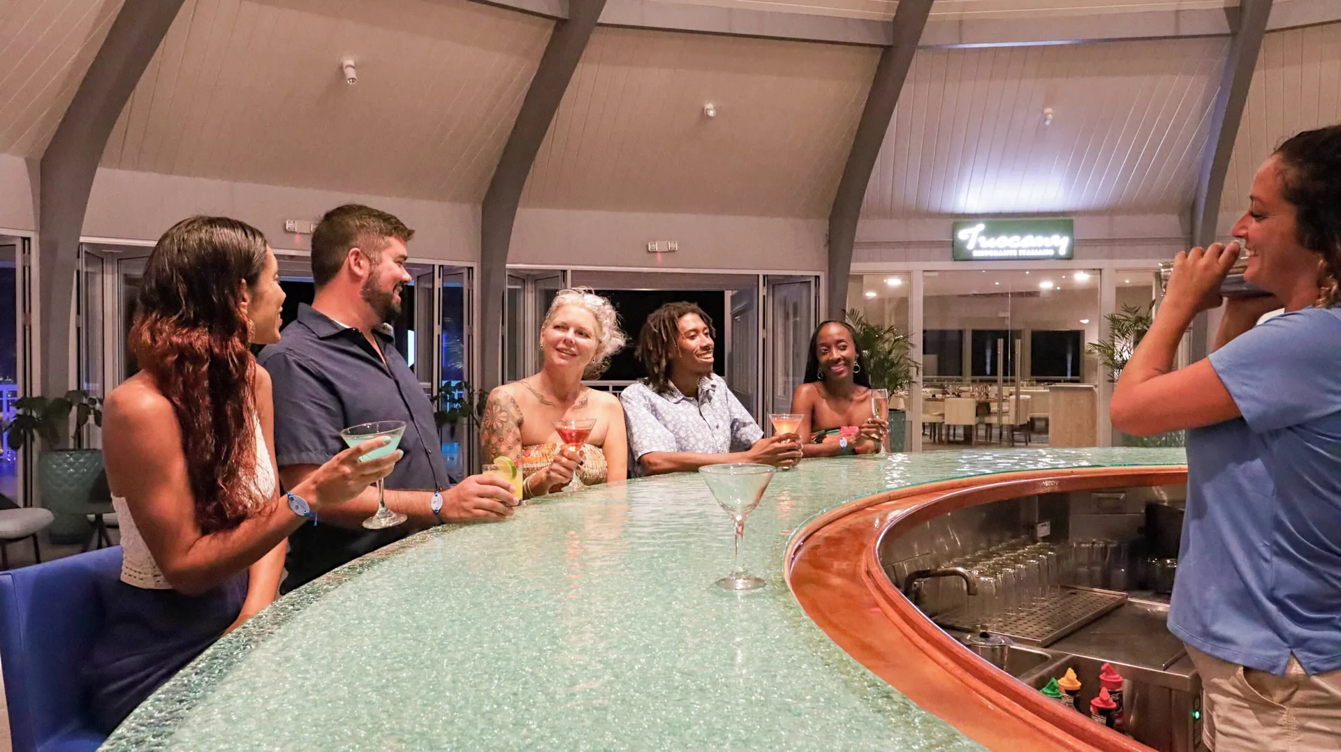 Guests enjoy cocktails at the curved bar inside Carina Bay Boutique Resort & Casino.