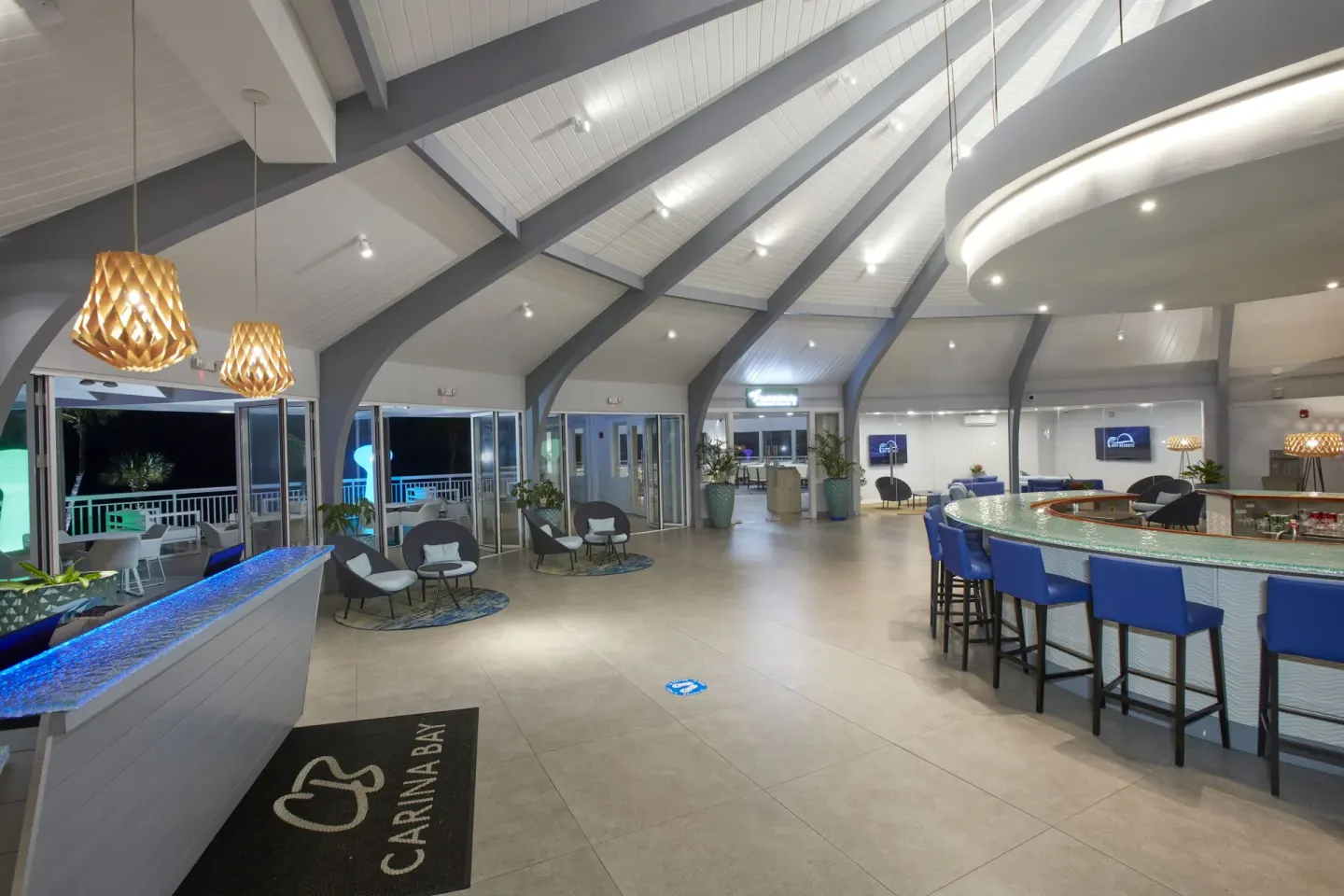 Open lobby bar area with blue stools at Carina Bay Boutique Resort & Casino.