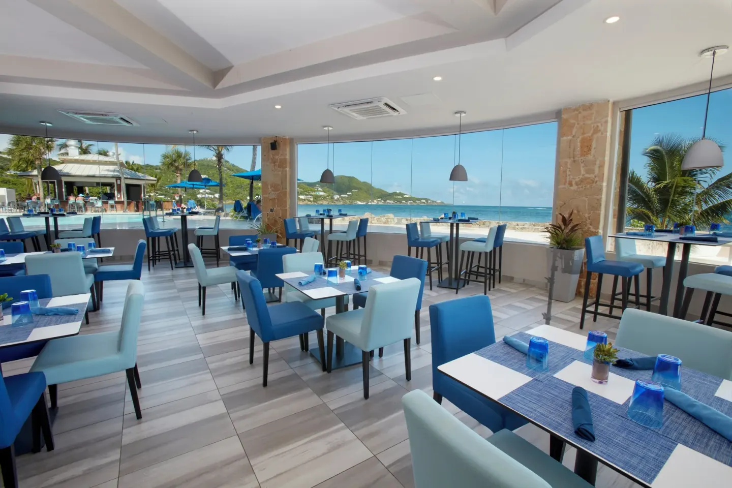 Ocean-view dining room with blue chairs at Carina Bay Boutique Resort & Casino.