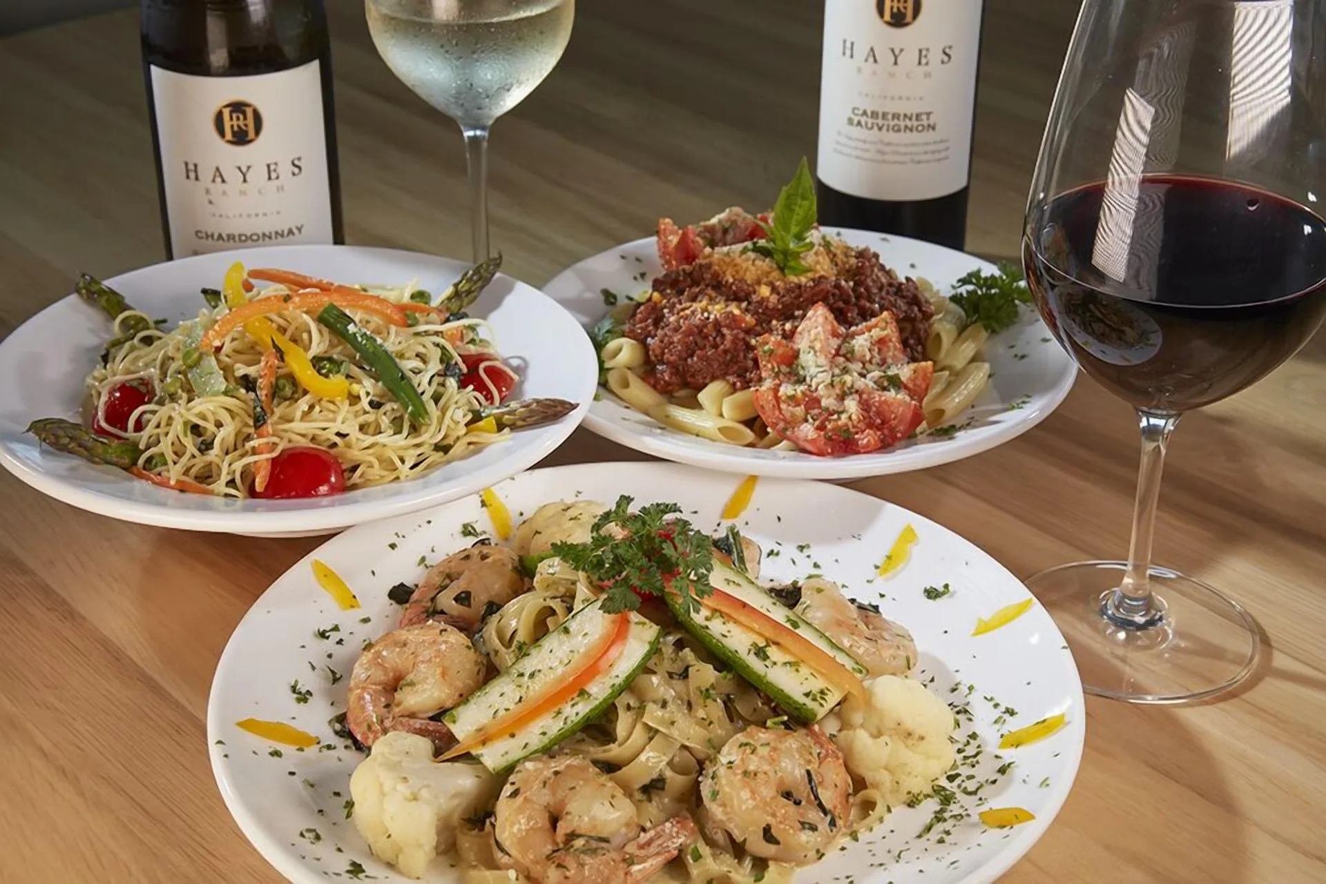 Pasta dishes and wine glasses on a table at Carina Bay Boutique Resort & Casino.