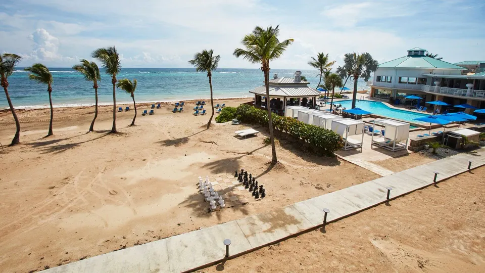 Beachfront room view over beach, pool, palms, and ocean at Carina Bay Boutique Resort & Casino.