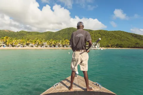 Boat crew member stands on the bow approaching the beach at Carlisle Bay.